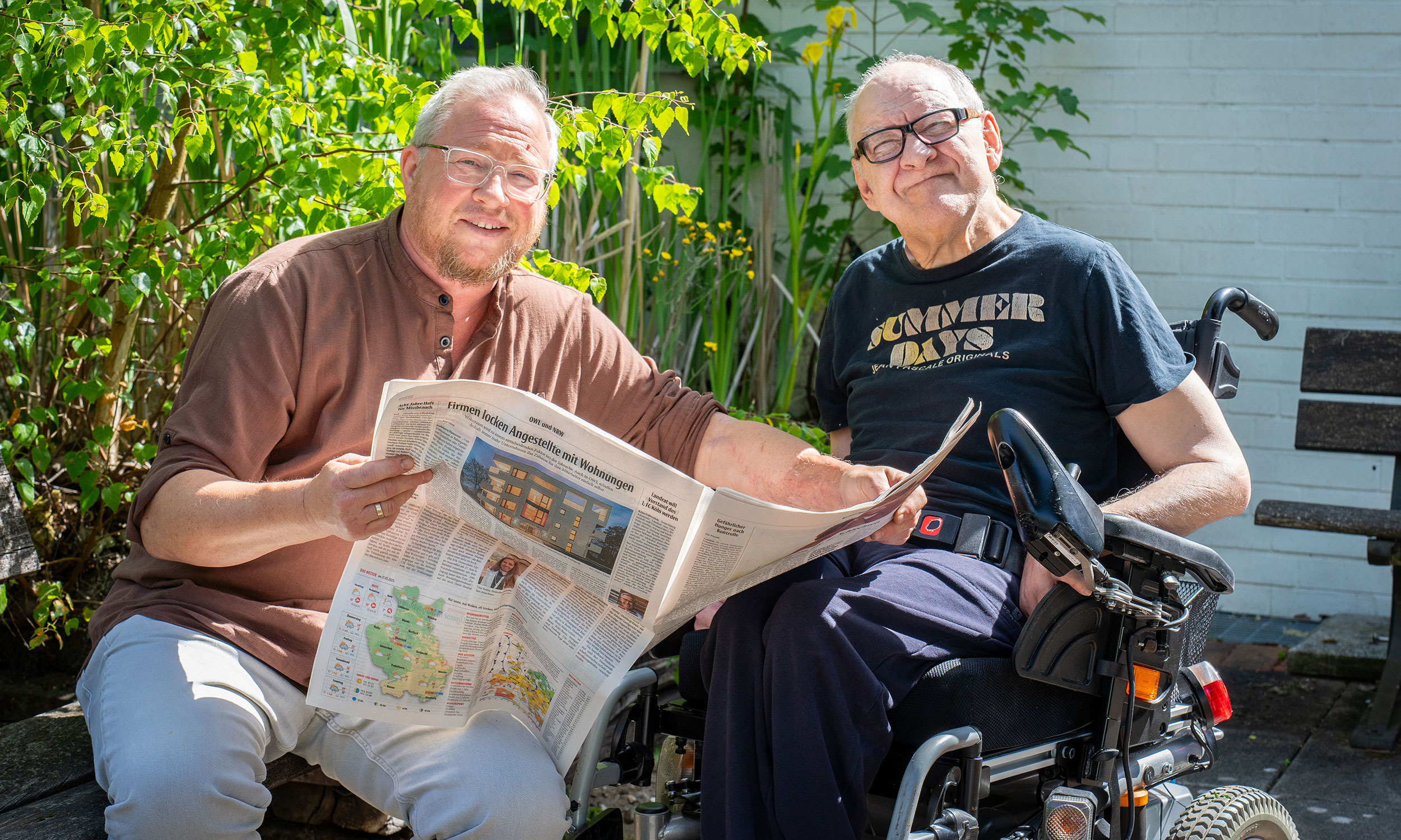 Betreuer und Bewohner der Einrichtung lesen gemeinsam Zeitung
